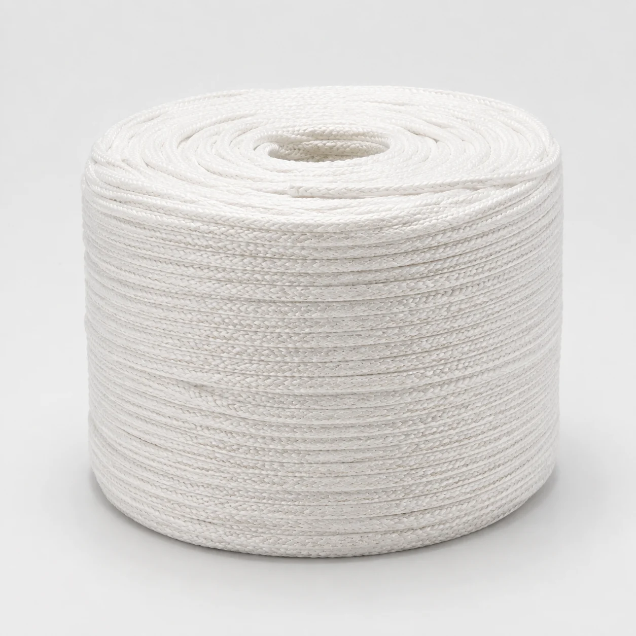Coil of natural white woven filler cord on a clean studio background.